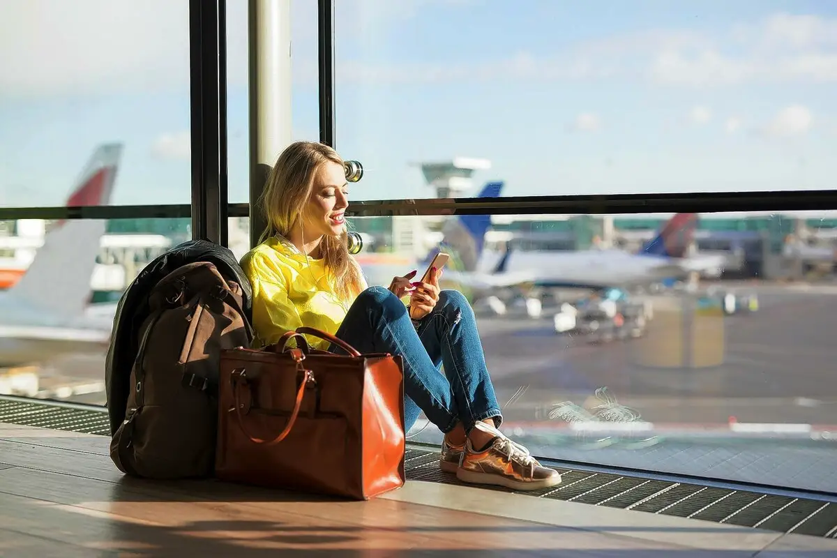 En rejsende, der slapper af i en lufthavnsterminal om natten med en rygsæk og en kop kaffe